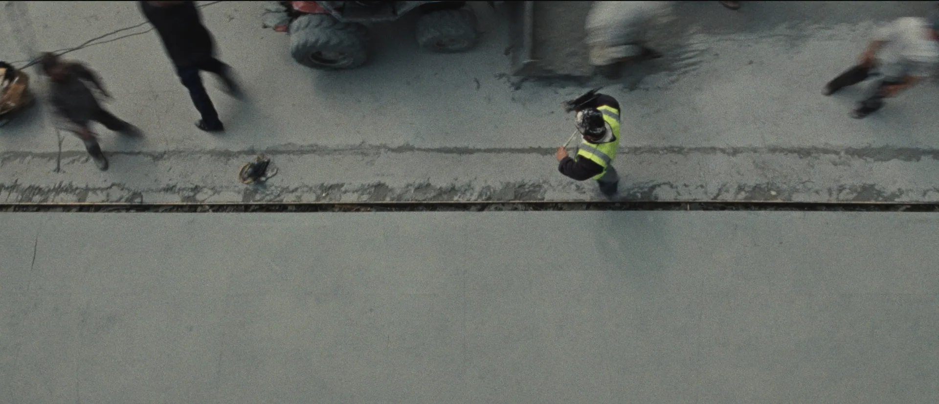 Builder walking a fresh concrete slab seen from above